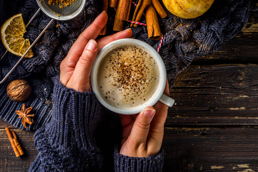 Autumn sweet hot drink, Chai Buttered Rum, Pumpkin Pie or Pumpkin Spice Coffee Latte. Cozy autumn background. Girl hold traditional latte cup in hands, on rustic wooden background.