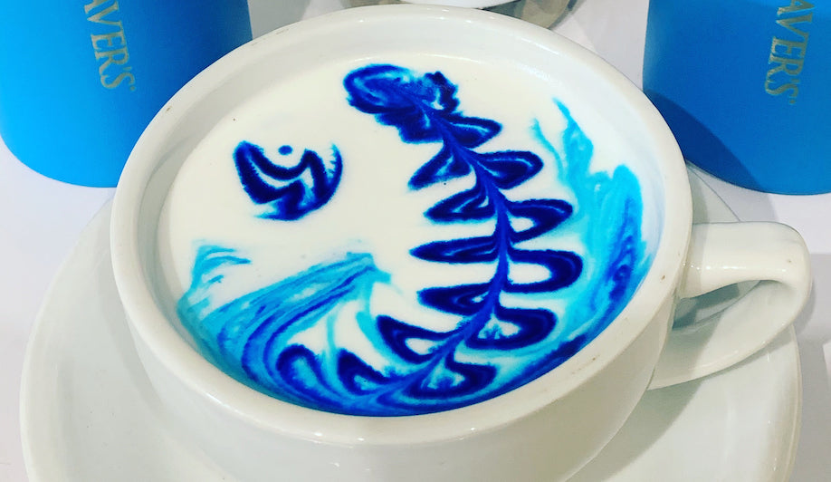 Large white coffee cup with latte art designs in blue