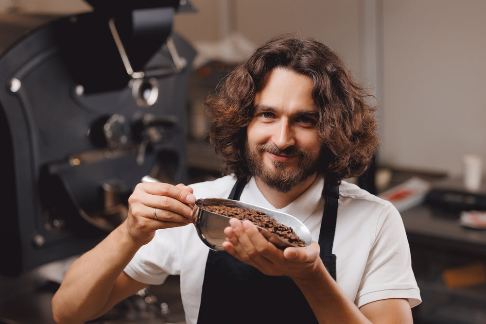 Barista standing next to coffee roasting machine.