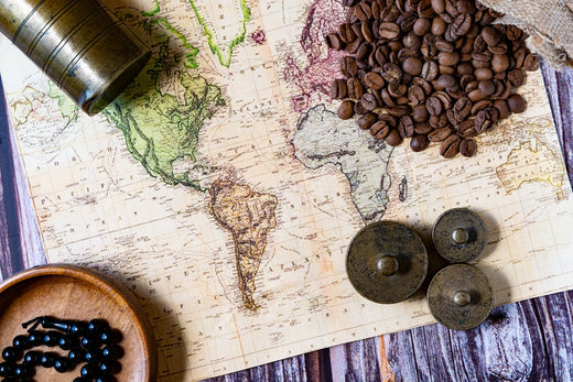 Coffee beans on world map with kitchen weights, old coffee grinder.