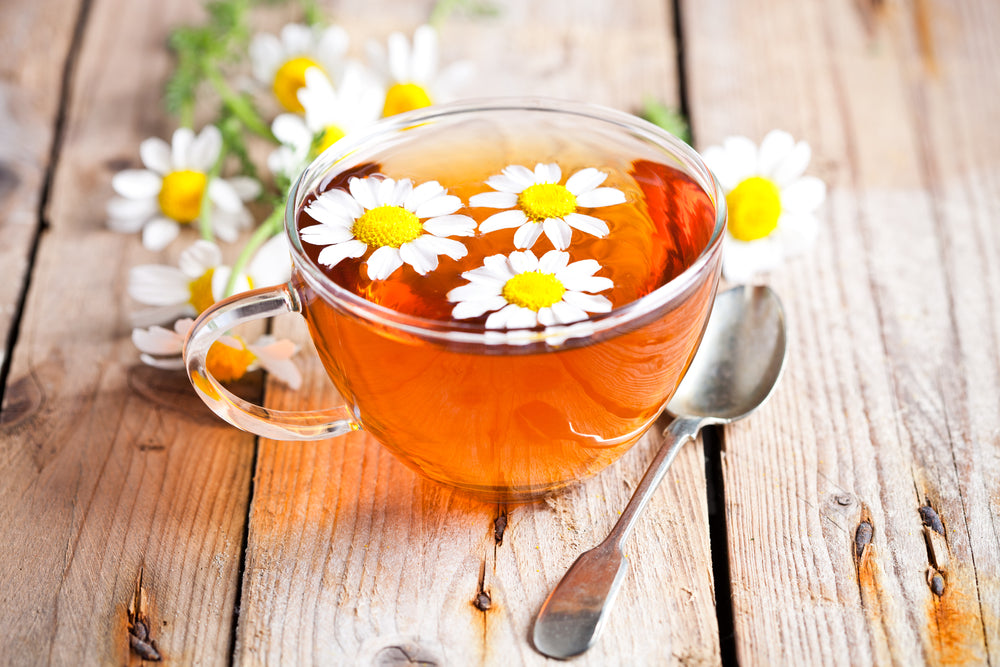 Cup of tea with chamomile flowers on rustic wooden background.