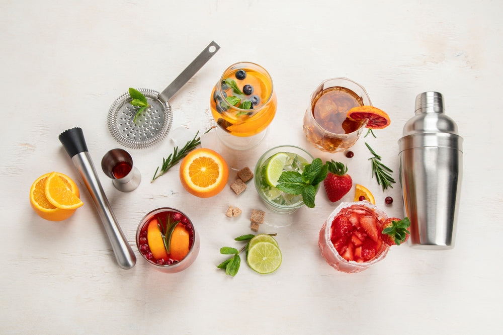 Different delicious mocktails on table with fruit, herbs and ice.