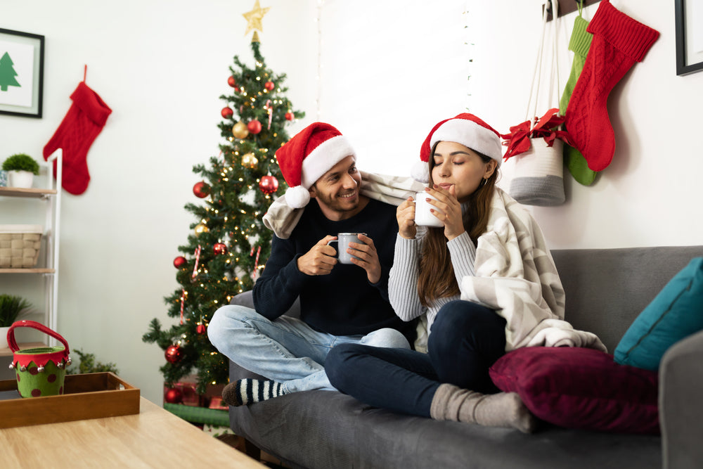 Happy Latin couple relaxing and enjoying Christmas together drinking hot coffee drinks.
