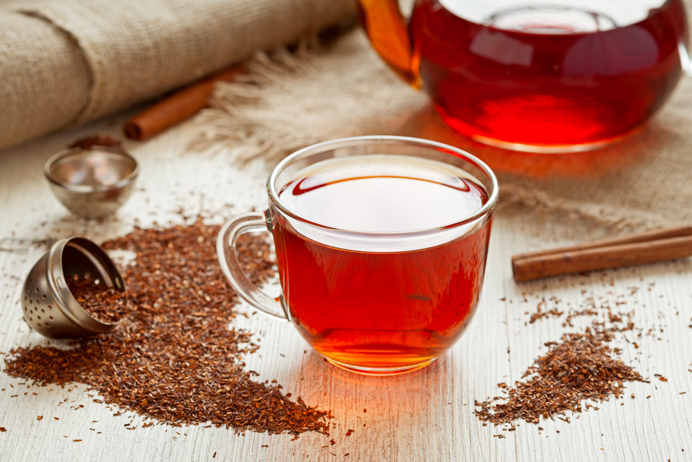 Healthy rooibus tea traditional south africa antioxidant beverage with spices on vintage wooden table in rustic style.