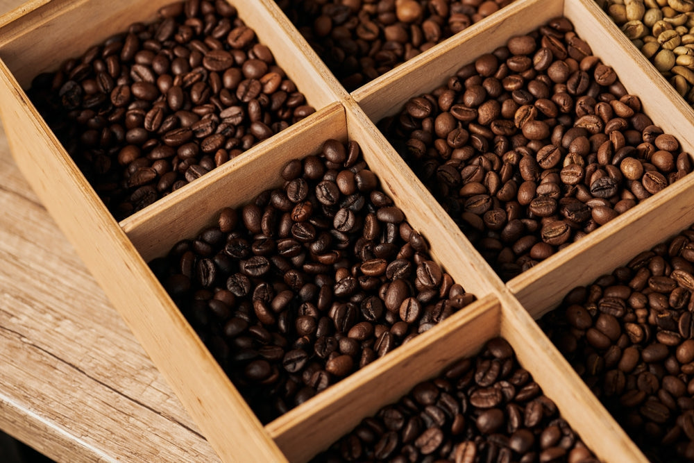 Light roasted coffee beans and dark roasted coffee beans in a wooden box.