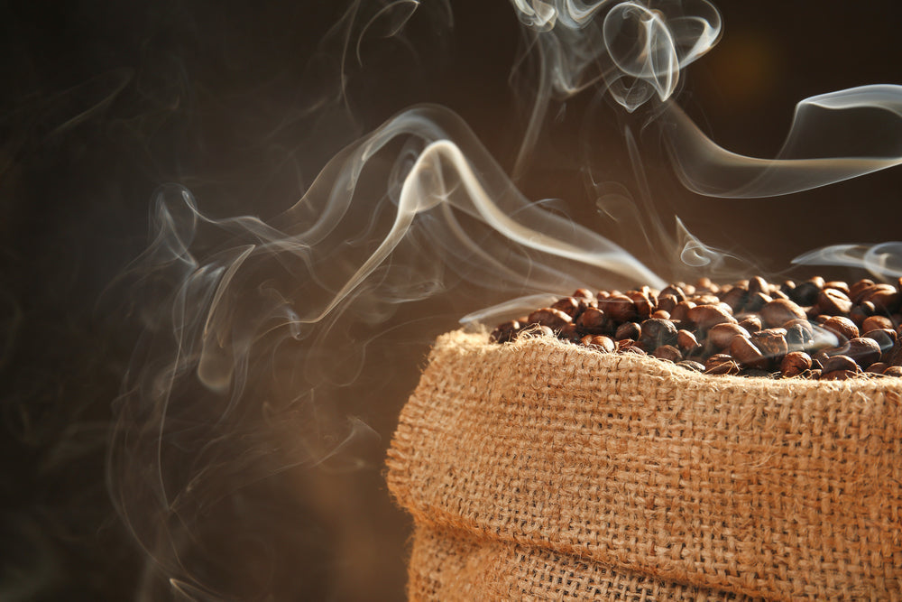Sack of mocha java roasted coffee beans on dark background, close up view.