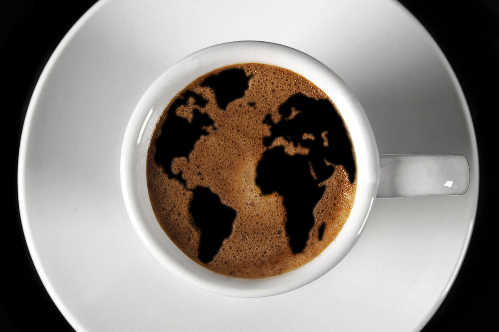 Shape of the world floating on top of a white cup of coffee.