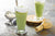 Two Matcha Smoothies in a tall glass with foam milk floating on top.
