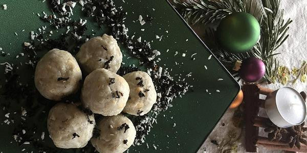 Earl Grey Protein Energy Bites on a square black tray with ornaments next to the tray.