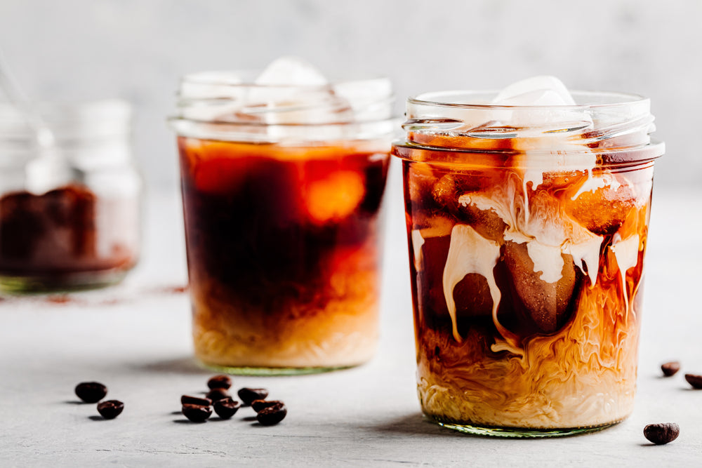 Almond Milk Vanilla Cold Brew Coffee Latte in glass jar on a gray stone background.