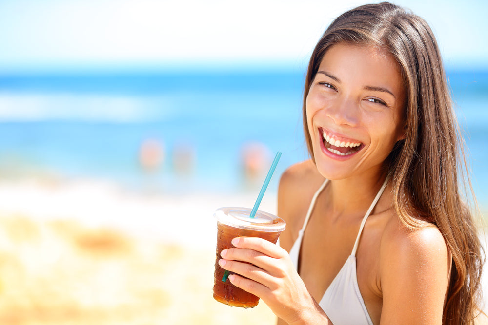 Beach woman drinking cold drink beverage having fun at beach party.