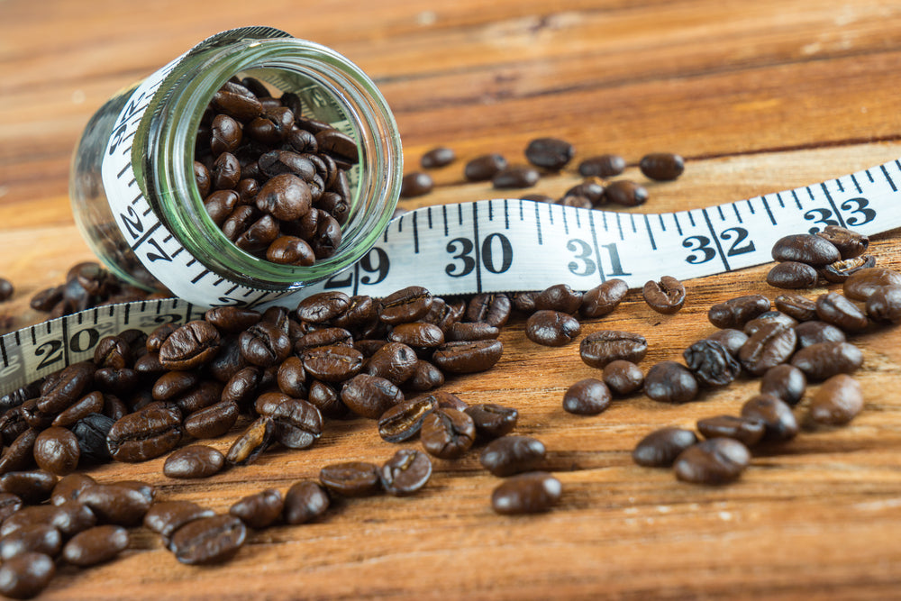 Coffee bean in glass bottle with tape measure on wooden table background.
