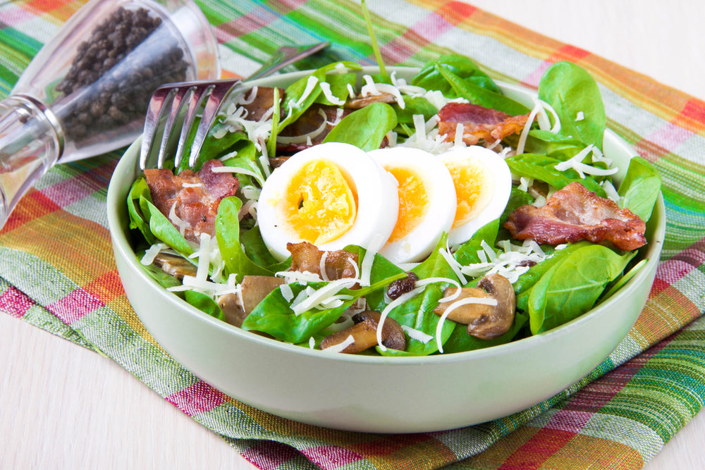 Fresh salad with bacon, mushrooms, cheese and boiled eggs with bright yolk.