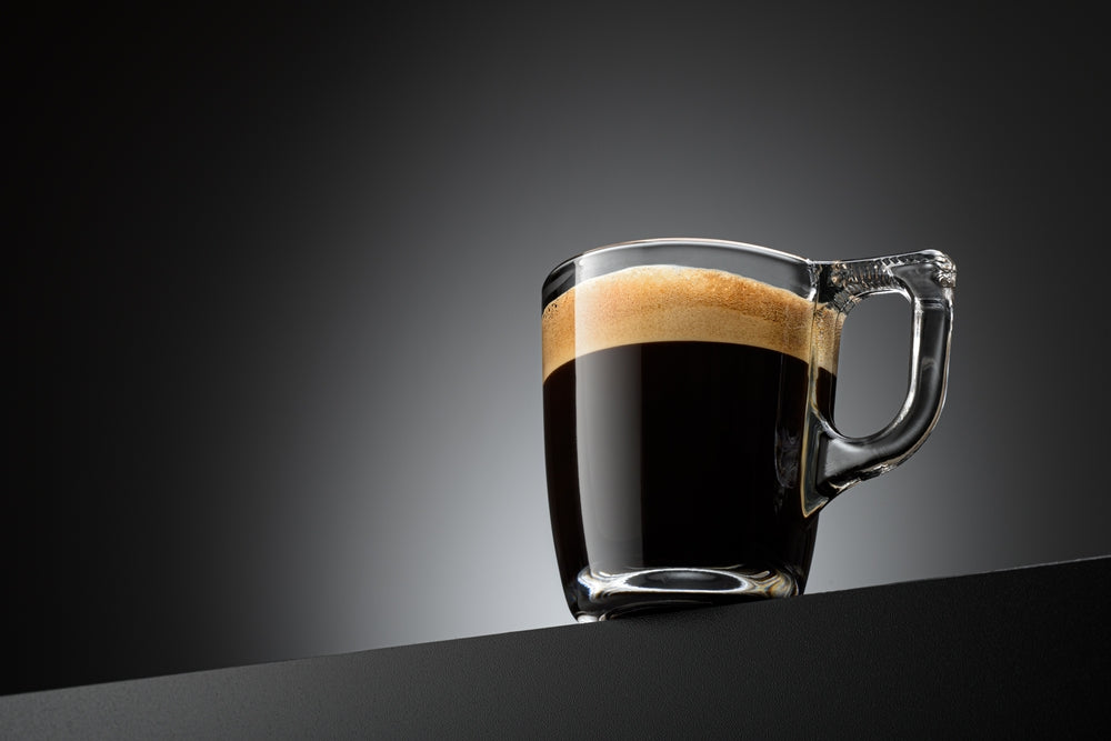 Espresso coffee mug on black table in a glass cup.