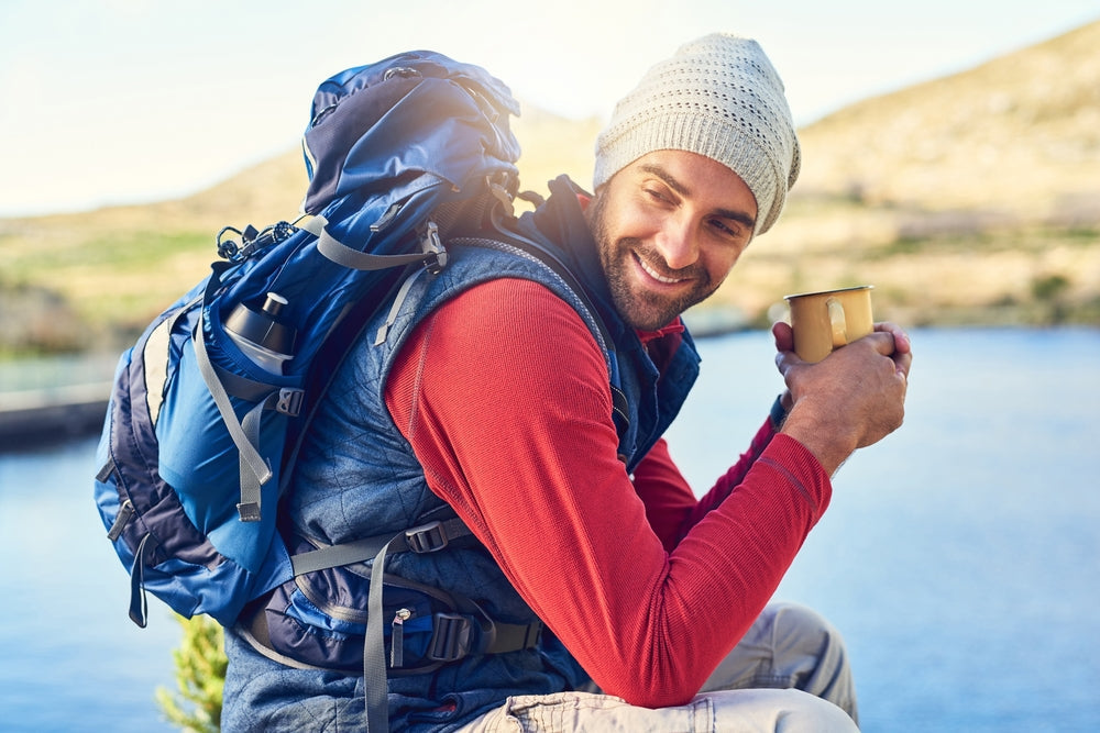  Happy man by lake with coffee in the morning before a hike.