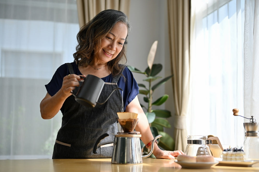Happy woman brewing coffee in the morning at home.
