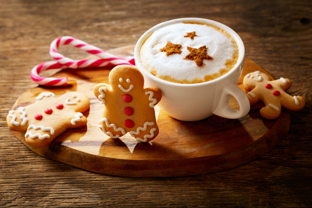 Holiday coffee drink a cappuccino coffee with stars drawing and gingerbread cookie on wooden board.