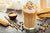 Iced caramel latte coffee in a tall glass with syrup and whipped cream.