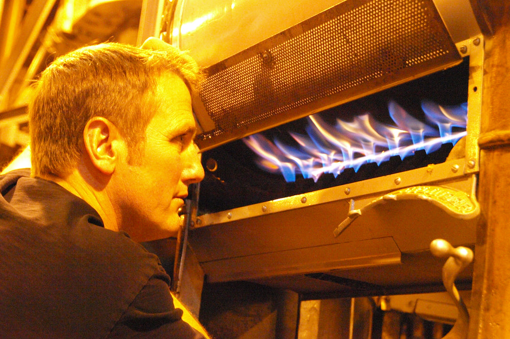 John Weaver looks into flames of a 1905 Royal No. 5 coffee roaster.
