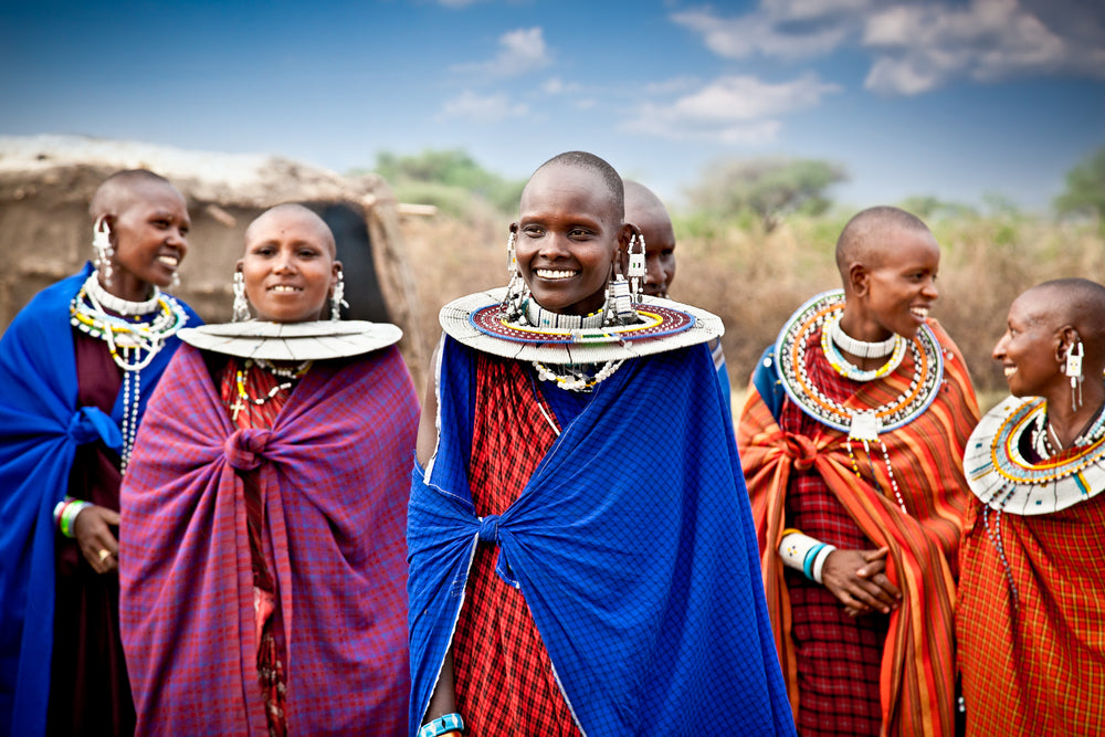 Women in brightly colored red and blue traditional African dress and jewelry.