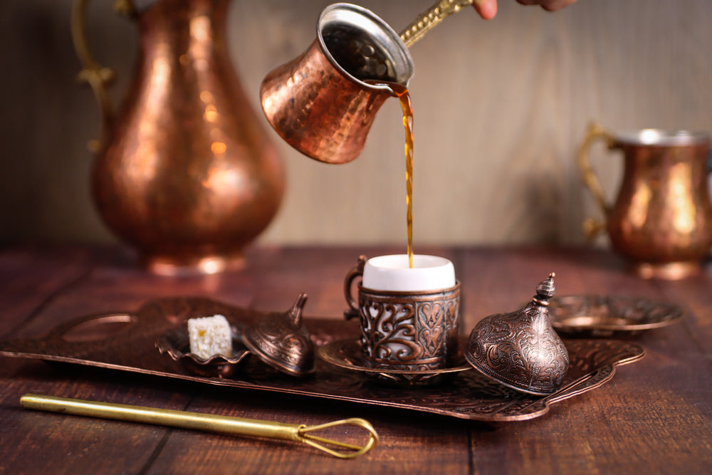 Pouring fresh Turkish coffee into a traditional Turkish cup.