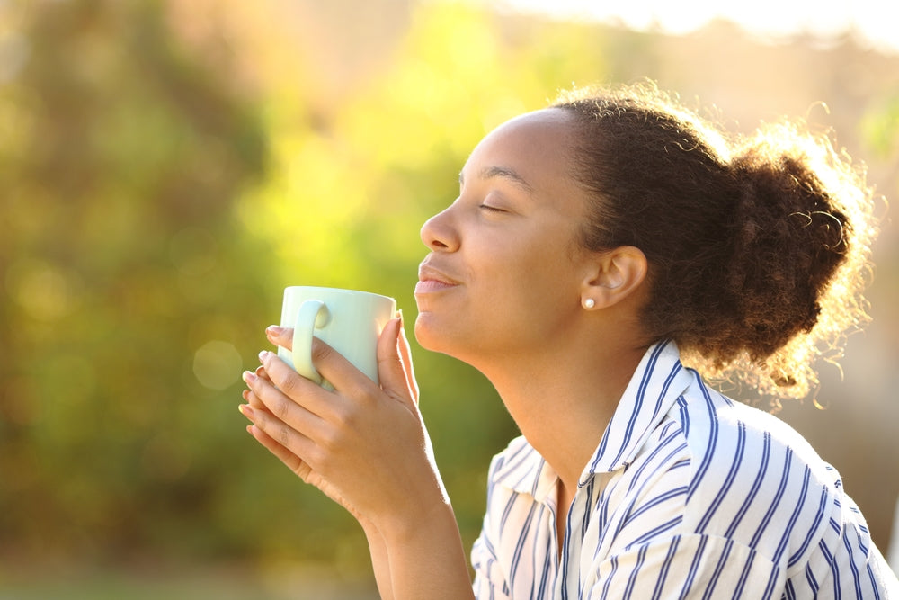 Profile of a relaxed woman drinking coffee and smelling aroma in a park.