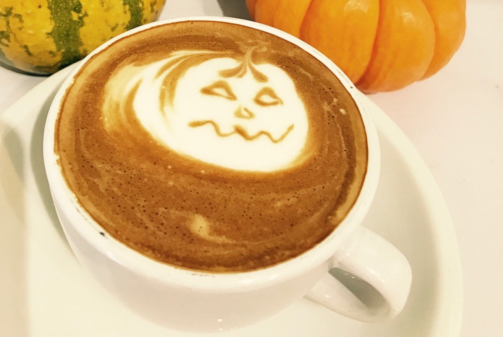 Pumpkin Spiced Latte with a pumpkin latte art in a white coffee cup on a saucer.