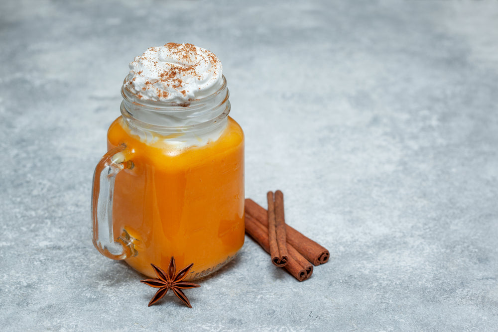 pumpkin smoothie, latte spices in a mason jar, cinnamon and star anise on a gray background.