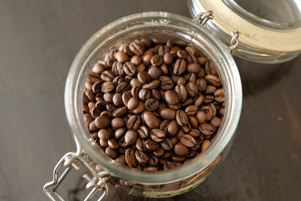 Roasted coffee beans in a glass storage bottle.