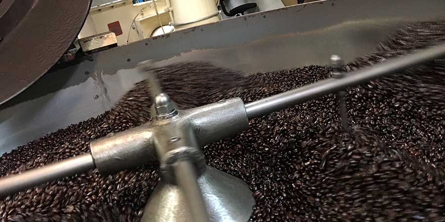 Fresh roasted coffee beans turning in the coffee roaster cooling tray.