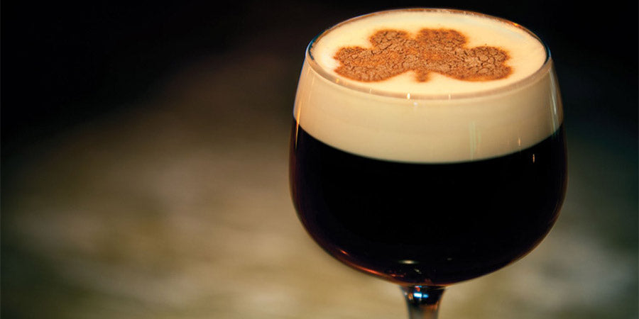 Original Irish Coffee in a glass with a four leaf clover impression on the milk.